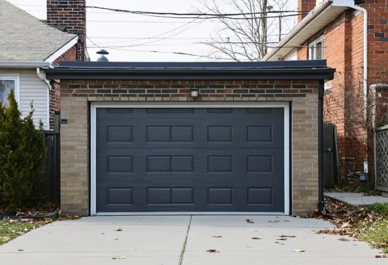 Detached brick garage with a flat roof beside a house
