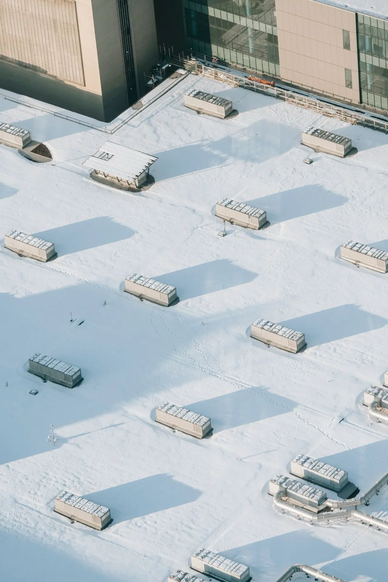 Snow-covered commercial flat roof with rooftop units seen from above